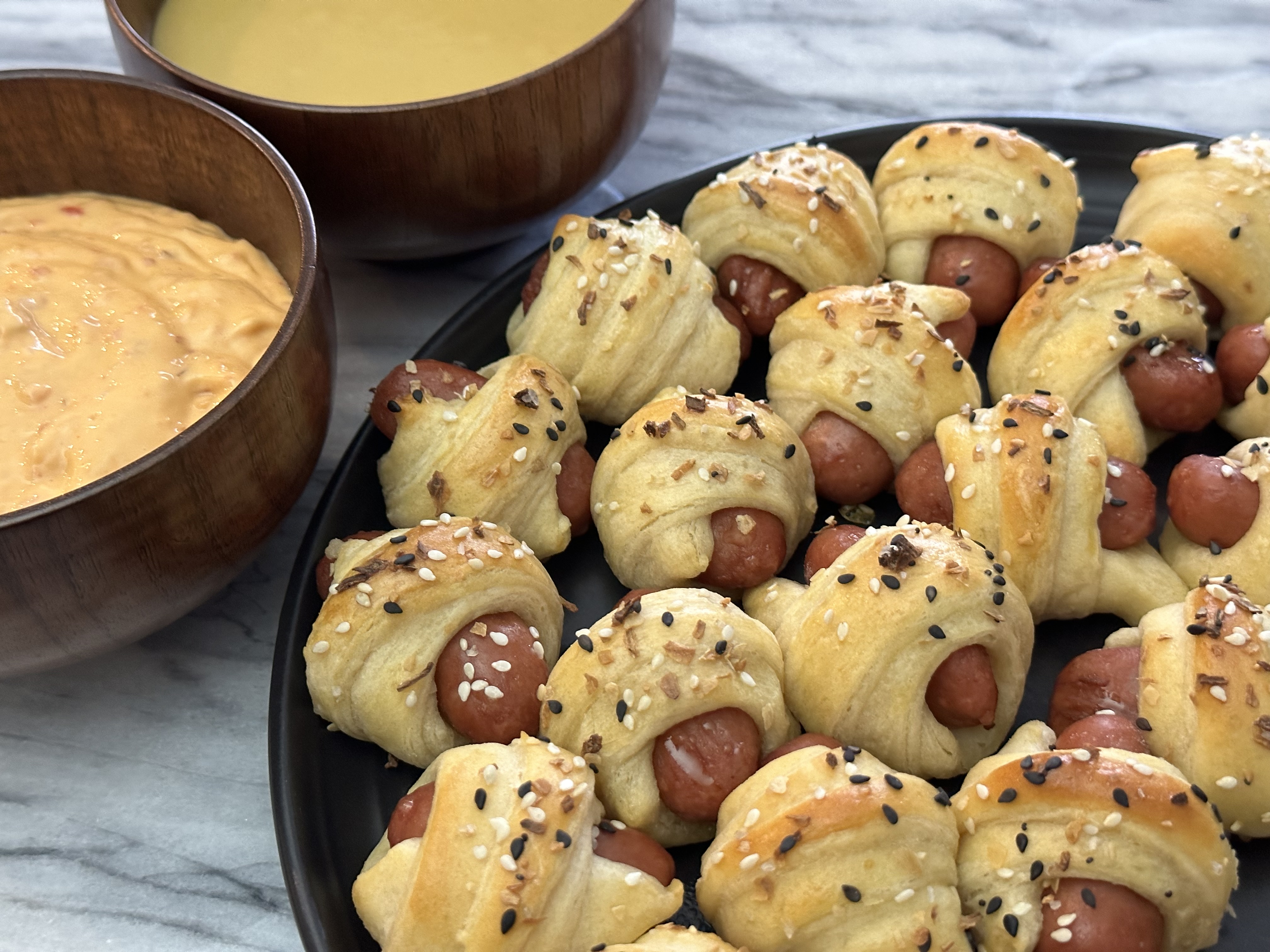 Pigs in a blanket on plate with dipping sauces.