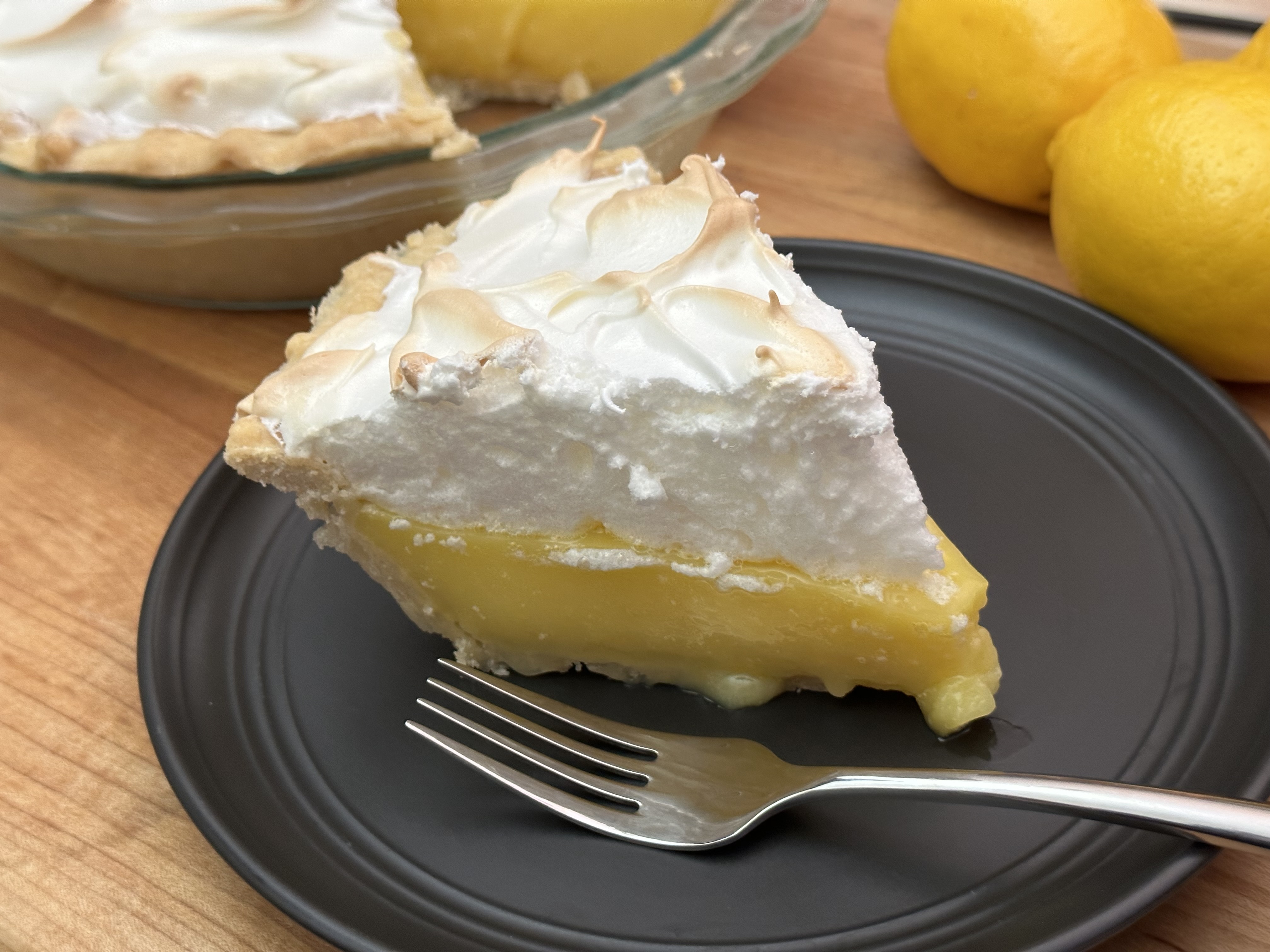 Slice of lemon meringue pie on black plate