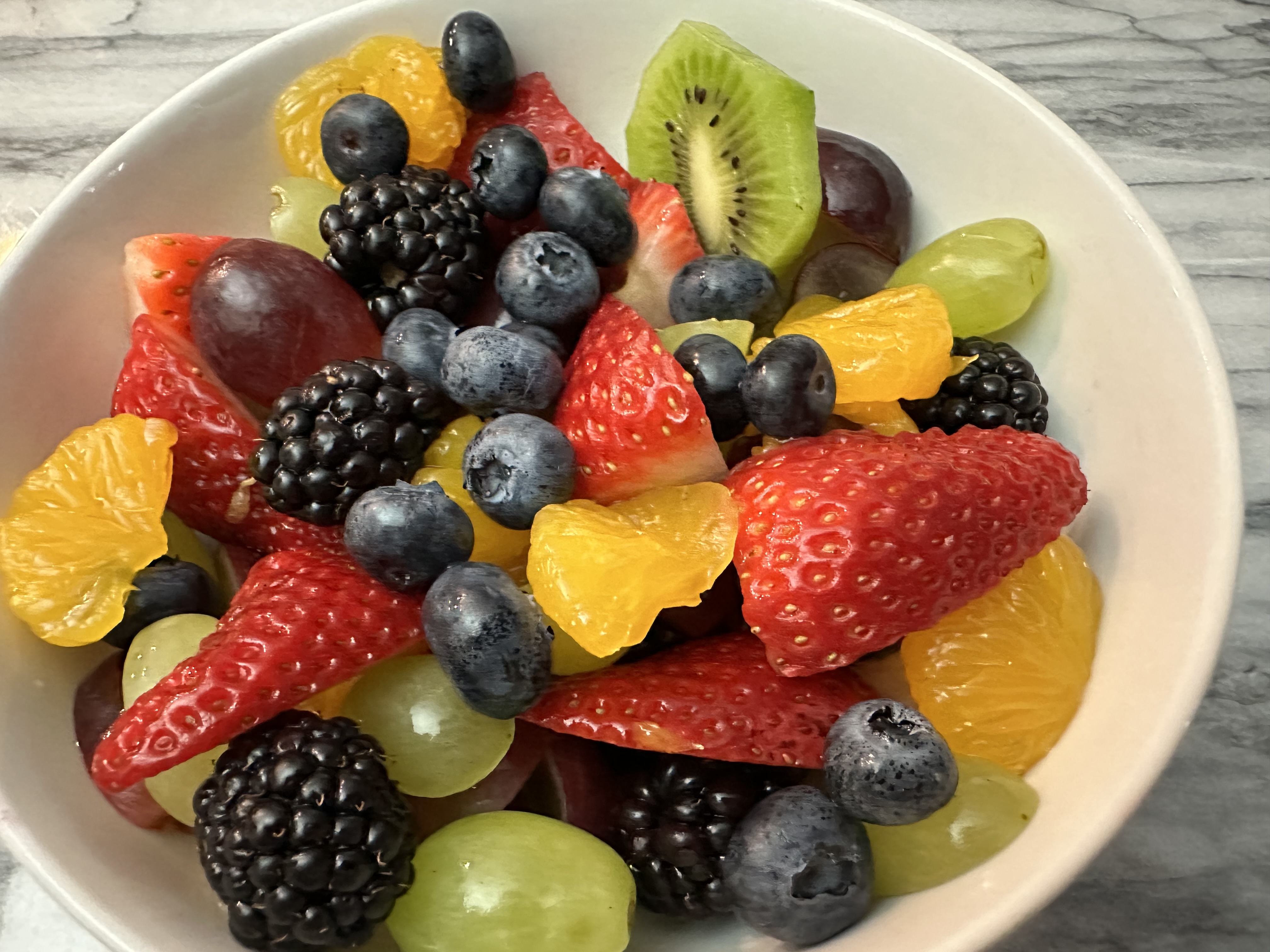 White bowl with an assortment of various fruits.