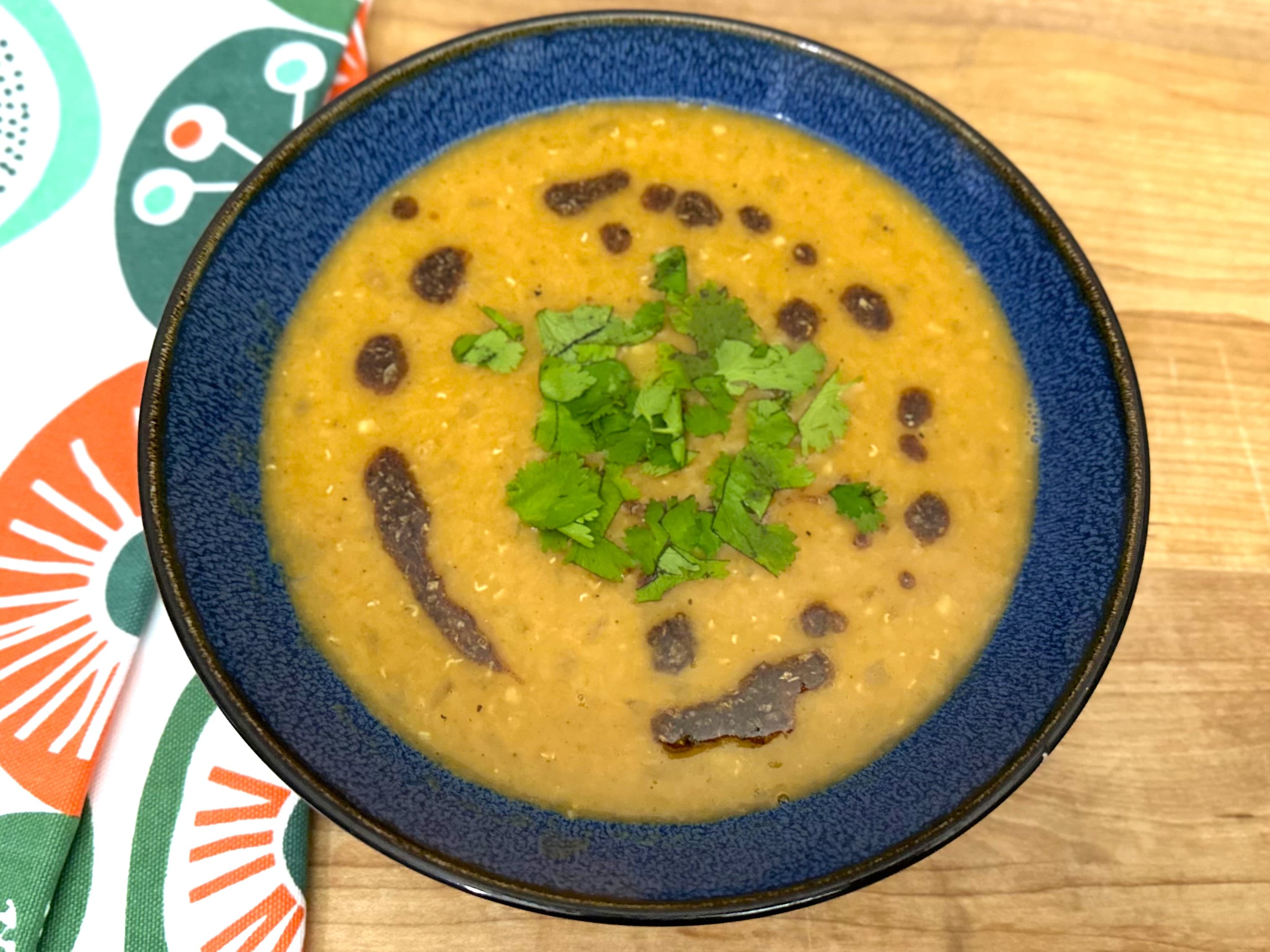 Red Lentil Soup in blue bowl on wooden board.