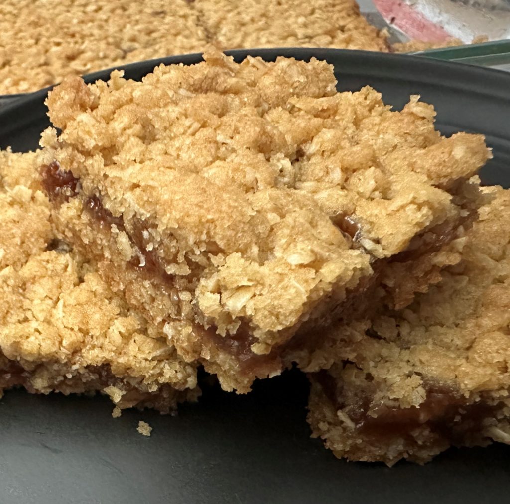 Three strawberry oat bars on a black plate.